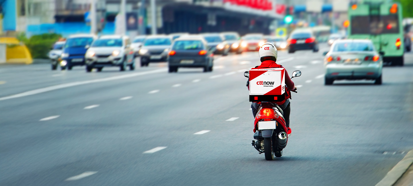 Estafeta numa mota a entregar uma encomenda enviada através do serviço CTT Now