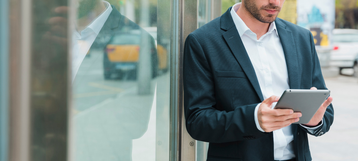 Senhor que está no meio da rua a mexer no seu tablet para converter os seus documentos para os canais online.